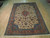 8'2 x 11'8 Tabriz rug displayed on light hardwood showroom floor showing ivory field and coral border
