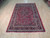 6'4" x 9'9" Persian Sarouk rug displayed flat on light hardwood showroom flooring
