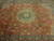 Close view of layered green and gold floral medallion on rustic coral Tabriz field