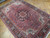 Angled view of hand-knotted wool Heriz rug showing pile depth, vine scrolls and navy border