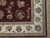 Corner detail showing ivory main border, guard stripes and black centered floral medallion on burgundy ground