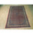Full 7x10 Persian Bijar rug photographed on warehouse wood floor, medallion centered in coral red field