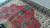 Coral red field with teal palmettes and ivory corner border seen in natural daylight