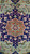 Close-up of navy medallion with terracotta rosette center, pink blossoms and green leafy tendrils