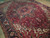 Angled view of semi-antique Persian village rug showing olive, ivory and brick red geometry