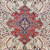 Close-up of the red and violet central medallion surrounded by tiny blossoms on ivory ground