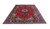 Large 10x13 Persian wool rug angled on white background showing red field and navy border