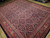 Angled view of large indigo and salmon wool rug showing border cartouches and even pile