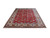 Angled floor display of large red Tabriz wool rug showing all-over floral field and ivory border
