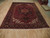 Antique pink Heriz medallion rug displayed on light wood showroom floor, angled full view