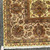 Fringed corner of the rug on pavement showing ivory gold ground with brown and green border bands