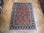 7' x 10' Persian rug displayed on herringbone parquet floor showing coral field and deep navy border