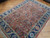 Angled view of semi-antique Heriz design rug highlighting short wool pile and warm salmon coral tones
