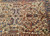 Angled view of cream field, camel accents and dense angular motifs on this 7x9 Heriz
