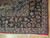 Corner detail of navy floral border, ivory guard stripes and cotton fringe on hardwood