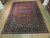 Deep red and midnight blue Persian rug displayed flat on light hardwood showroom floor