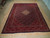 10x13 Persian Tabriz rug photographed flat on light wood flooring showing burgundy border and navy field