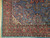 Corner detail showing multi banded salmon border, ivory rosettes and teal selvage of the wool rug