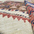 Close-up of hand-knotted wool pile with salmon sawtooth outline against creamy ivory open field