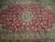 Close view of teal blue medallion rosette surrounded by cream palmettes on deep red ground