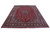 Red and navy Kashmar wool rug photographed at an angle showing medallion, spandrels and ivory vinery