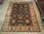 9 x 12 hand-knotted wool rug displayed on light wood showroom floor beside rolled rugs