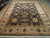 9 x 12 black Peshawar area rug angled on hardwood showroom floor with ivory floral border