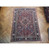 Full overhead photograph of this 7x10 red Persian rug laid flat on light parquet flooring