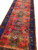 Perspective down the runner highlighting green latch hook medallions against a rich tomato red ground