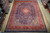 9'8" x 13'4" Persian Sarough rug displayed on warehouse floor beside rolled Oriental rug stacks