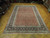 Large 8x12 wool area rug laid flat, salmon floral field with inky black main border