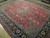 Angled view of red Persian rug revealing allover palmette vinework, teal accents and dense wool pile