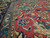 Close-up of teal minor border, ivory guard stripes and hand-knotted wool pile on red ground