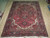 7'4" x 11'3" Persian Heriz rug laid flat on a light wood warehouse floor