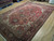 Angled view of hand-knotted wool Heriz rug showing deep red field and navy border
