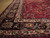 Corner detail of the navy main border with ivory guard stripes and pink floral scrollwork