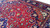 Low angle pile detail showing crimson field, leaf motifs, gold accents and dense hand-knotted wool