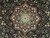 Close-up of ivory and burgundy central medallion with green rosette detail on black wool pile