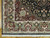 Corner detail showing burgundy spandrel, ivory main border, green palmettes and hand-tied cotton fringe