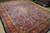 Angled floor view of large 10x13 hand-knotted wool rug with deep orange palmette border