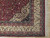 Corner detail showing ivory main border with woven bird figures, burgundy guard stripes and hand-tied fringe