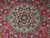 Close-up of the star medallion in ivory, Como green and navy on crimson wool pile