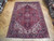 Semi-antique Heriz rug displayed on parquet showroom floor showing navy border and geometric medallion pattern