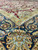 Close-up of navy border palmette in sage green, gold and coral beside burgundy field