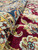 Folded pile detail revealing dense wool knots, wine red ground and multicolor floral scrollwork