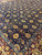 Burgundy and slate blue borders frame the navy field of this all over floral Indian rug