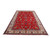 Red field oversize Tabriz rug photographed at an angle showing ivory palmette border and even pile