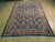 7' x 10'5" Persian Sarouk rug displayed on light wood floor showing full navy floral design