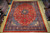 9'9" x 13' Sarouk rug displayed flat on light wood floor in Freeport warehouse