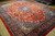 Angled view of the 10x13 hand-knotted wool rug showing navy border and salmon red field